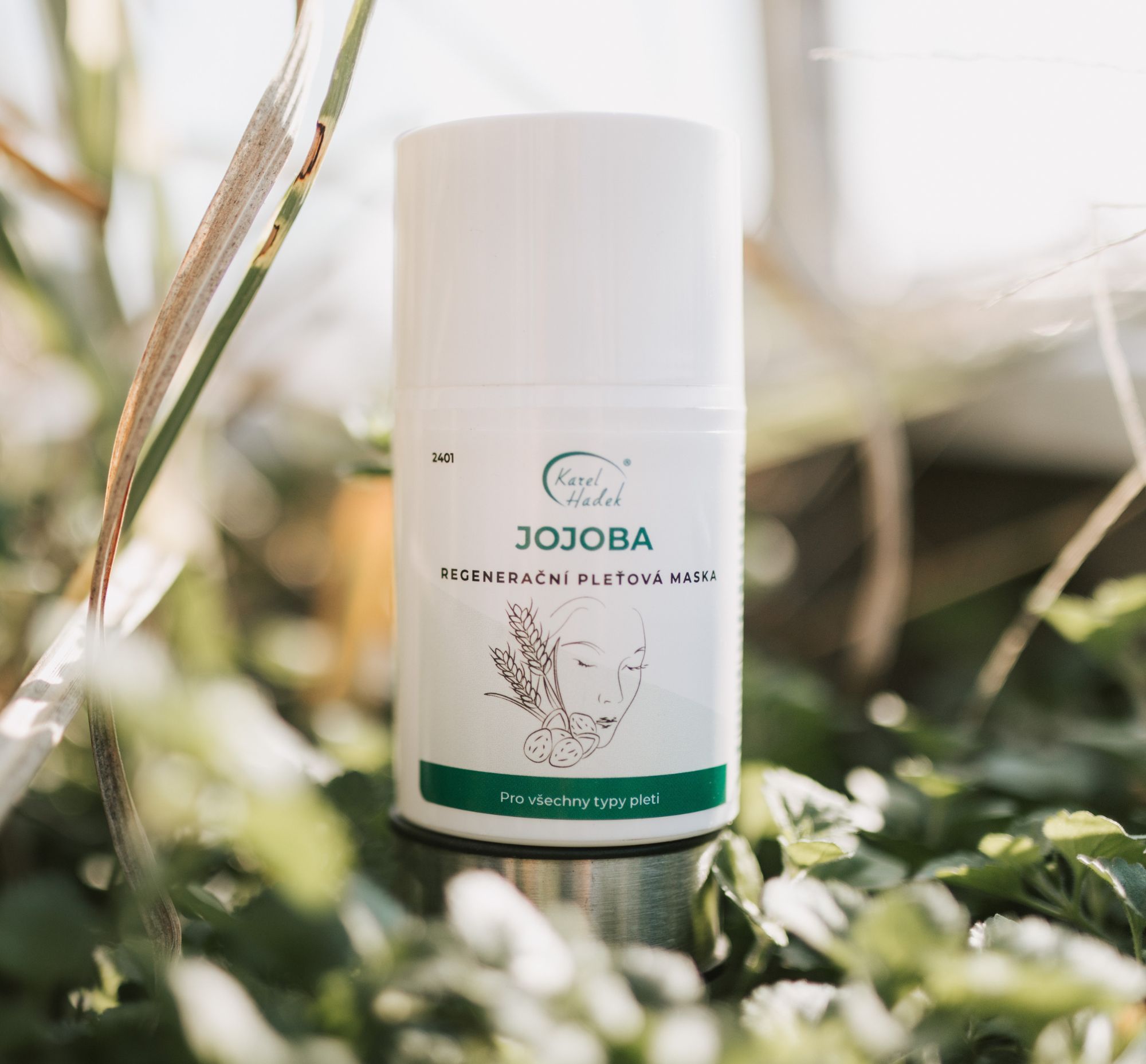 Hydratační maska JOJOBA ležící v zelené trávě.