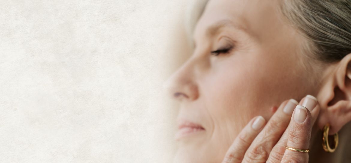 Žena sahající si rukou na tvář.